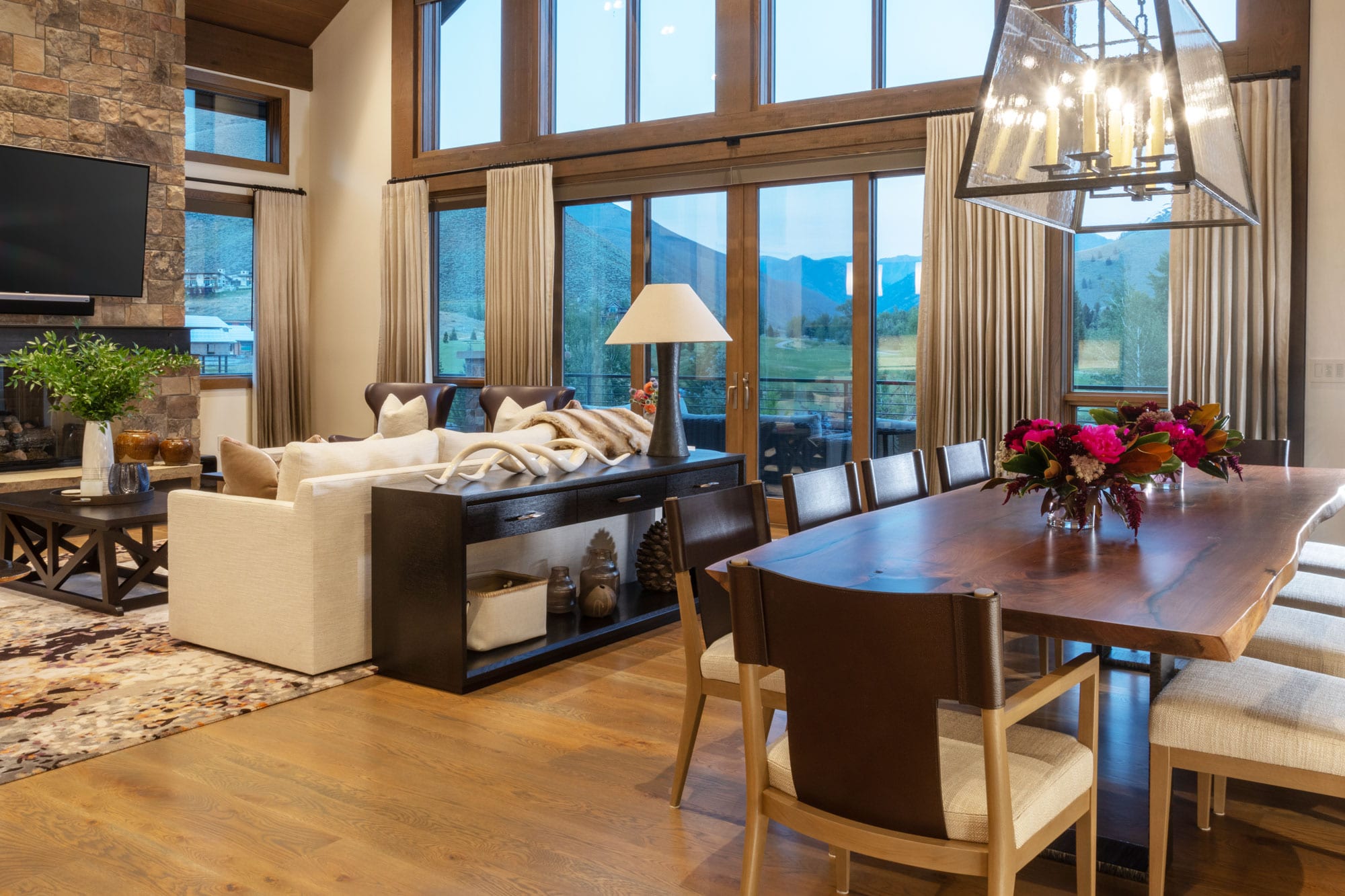 A great room with a wall of windows, a sofa and a live-edge dining table, from the Refined Chic project