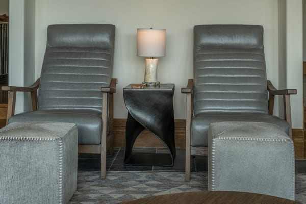 Pair of grey leather recliners with hide ottomans and a sculptural side table