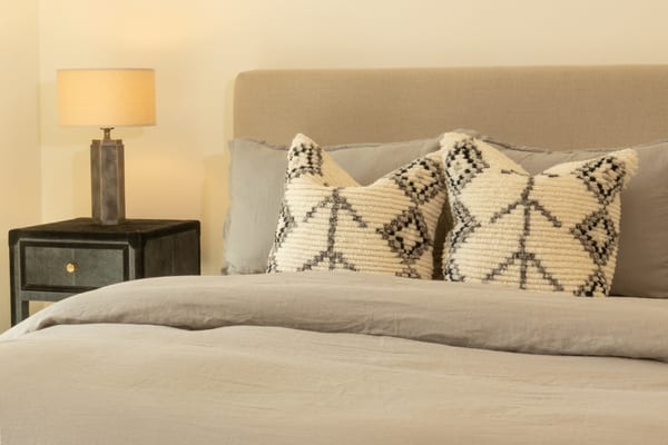 Bed with a linen headboard and patterned wool pillows