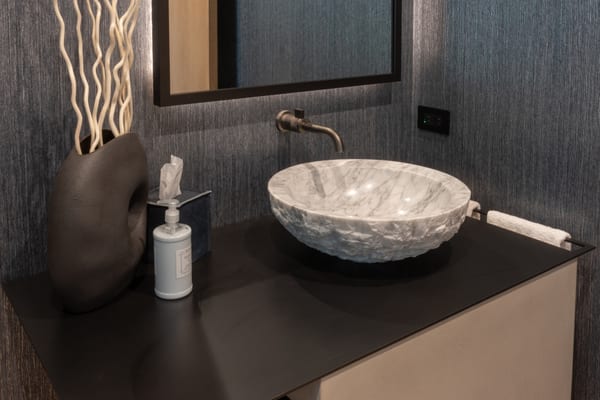 Stone vessel sink on a black floating vanity with a bronze wall faucet