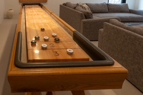 Wood shuffleboard table beside a grey sectional