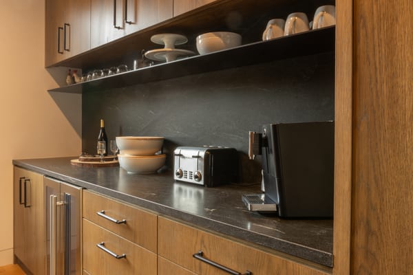 Coffee bar with oak cabinets, open shelves and a dark stone backsplash