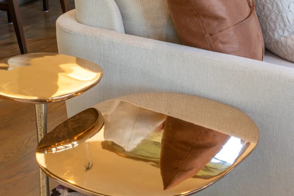 Polished brass side tables beside a cream sofa