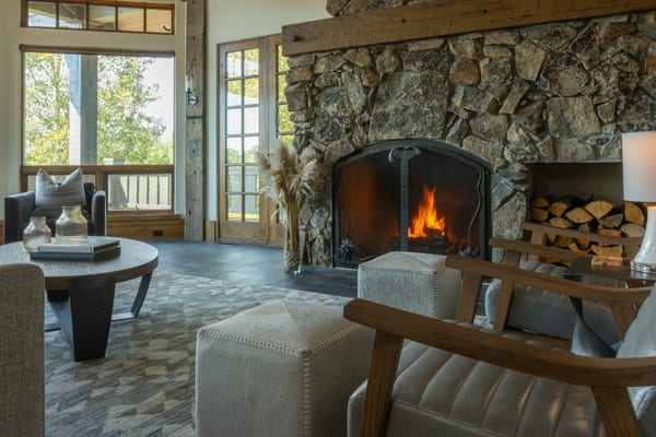 Stone fireplace with a log nook, leather and wood chairs and a round coffee table