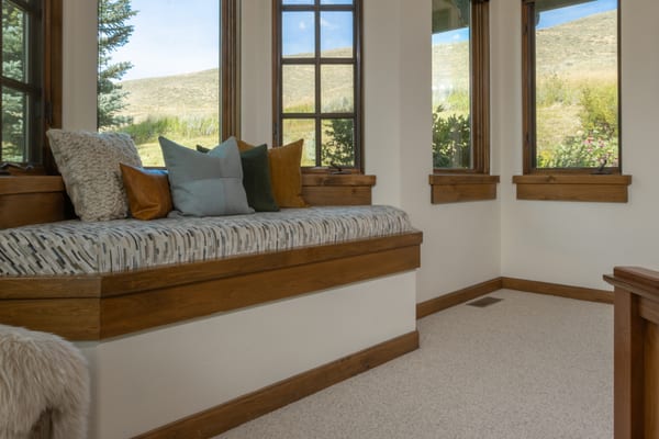 Window seat with a patterned cushion and pillows overlooking the hills