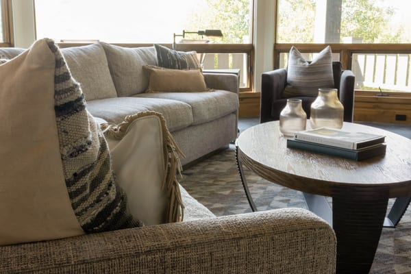 Linen sofa with woven and fringed pillows beside a round coffee table