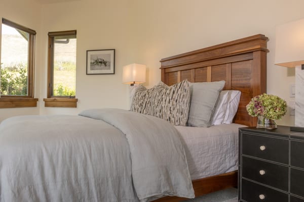 Bedroom with a walnut panel headboard, black leather nightstands and hillside views