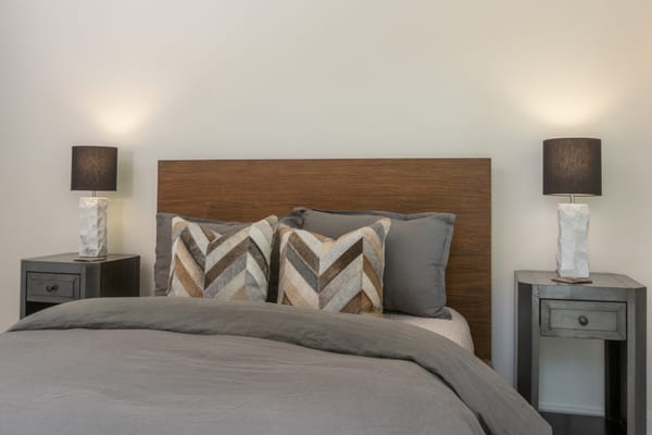 Bed with a walnut headboard, chevron hide pillows and matching nightstands