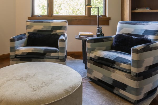 Pair of ikat-patterned armchairs and a round ottoman by the window