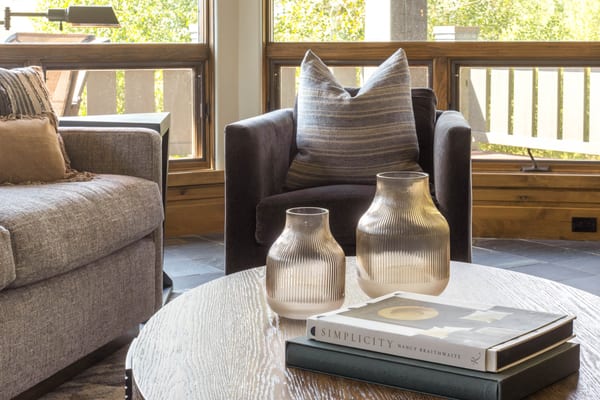 Charcoal armchair and ribbed glass vases on a round wood coffee table