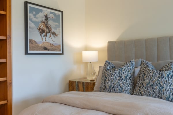 Bed with a channel-tufted headboard below a framed cowboy photograph