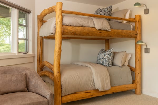 Log bunk beds with grey bedding and wall-mounted reading lights