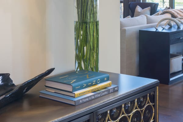 Sideboard with brass-trimmed circle doors and a tall vase of white flowers