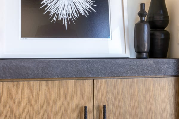 Framed black and white flower print above an oak cabinet with a stone top