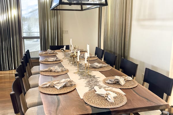 Live-edge dining table set for dinner under a glass lantern chandelier