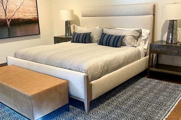 Bedroom with an upholstered bed, a leather bench and a navy patterned rug