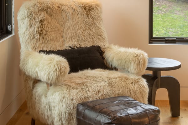 Shaggy sheepskin armchair and leather pouf in a corner by the window