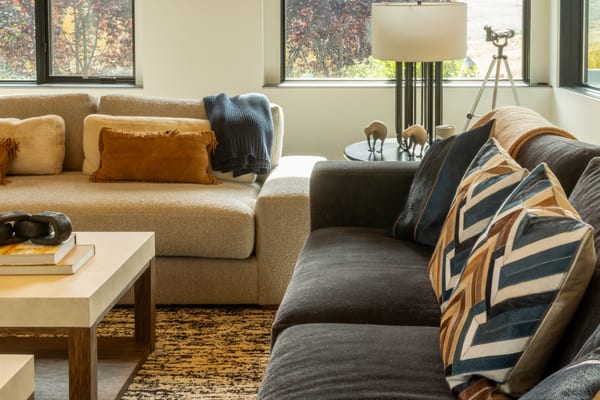 Cream and charcoal sofas with leather and patterned pillows, and a telescope by the window