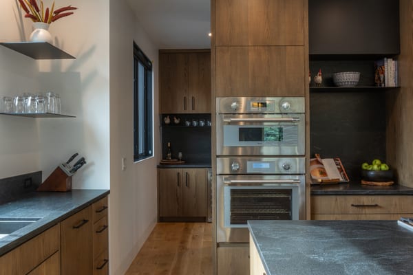 Kitchen with oak cabinets, double wall ovens and a dark stone countertop