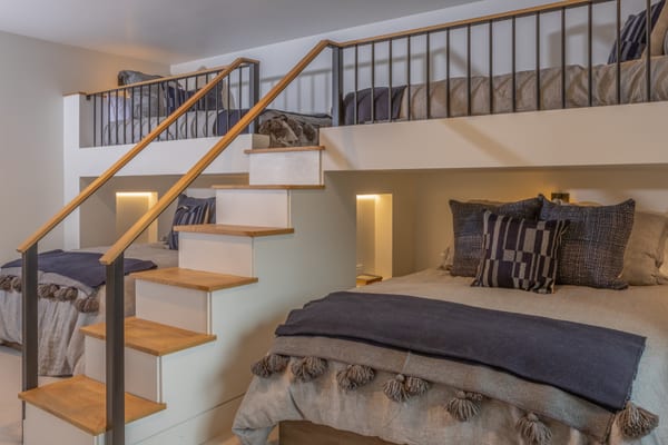 Bunk room with beds on a loft above and below, reached by oak stairs