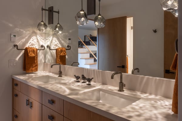 Double vanity with oak cabinets and faceted glass pendants casting light patterns