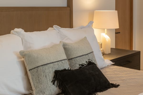 Close-up of white bedding with striped and fringed pillows