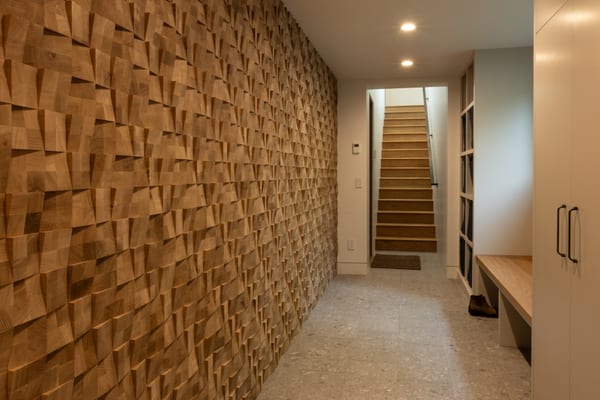 Hallway with a carved wood feature wall leading to a staircase