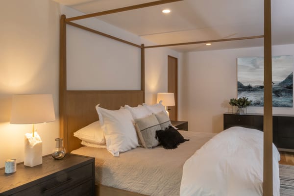 Four-poster bed with alabaster table lamps and a seascape painting
