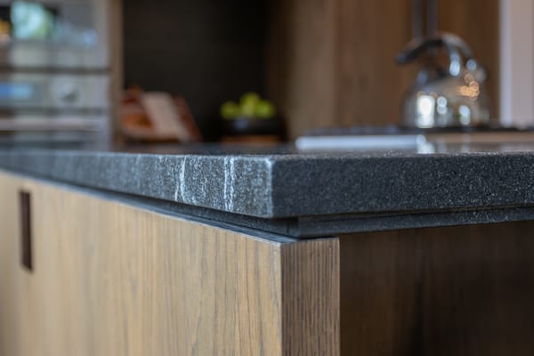 Close-up of a dark stone countertop edge on an oak island