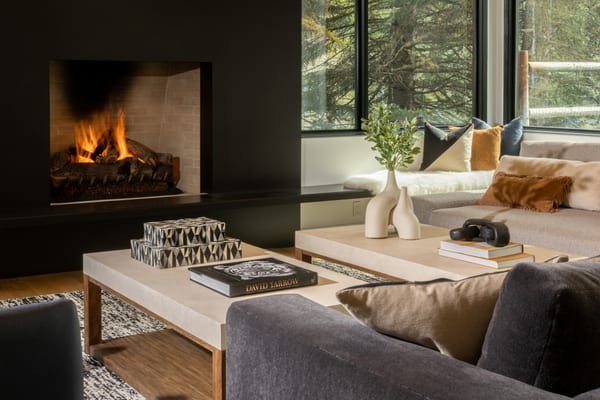 Fireplace and window seat, with sculptural vases and books on the coffee tables
