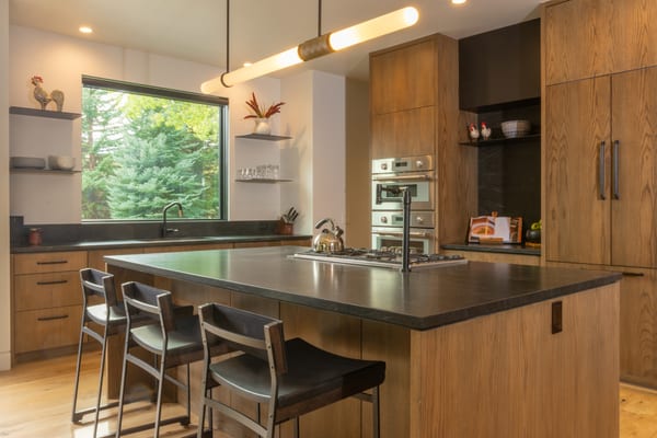 Kitchen with oak cabinets, a dark stone island with bar stools and a picture window