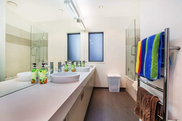 Bathroom with two vessel sinks on a long white vanity and frosted windows