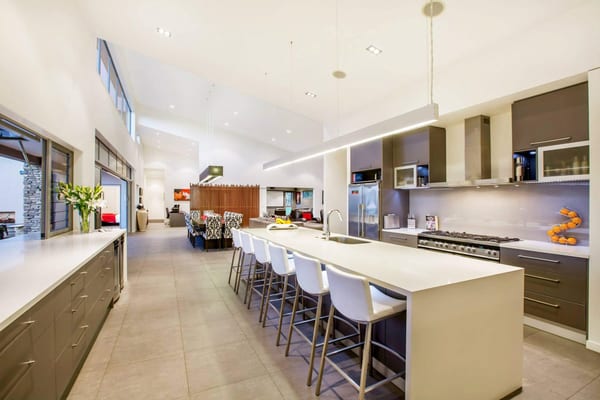 Long white kitchen island with bar stools, open to the dining table and living room